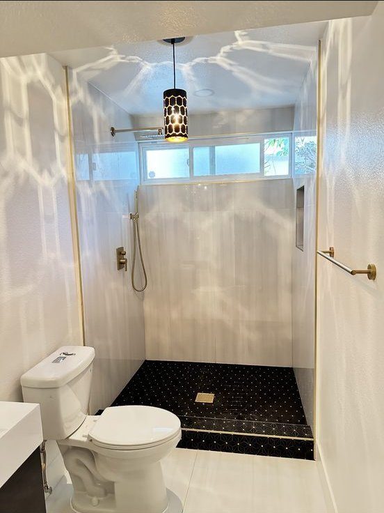 Walk-in shower with gold fixtures and black mosaic floor